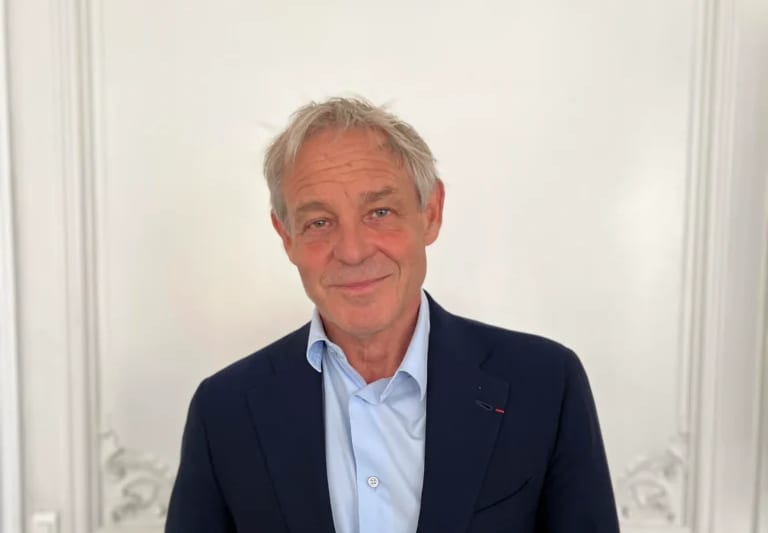 Portrait de Philippe Rosenpick, souriant, en veste bleu marine et chemise bleu clair, devant des boiseries blanches.